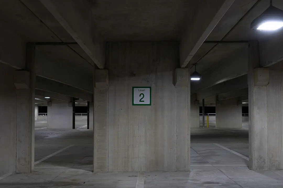 Carteles de señalización para parkings indicando dirección obligatoria, salidas y límite de velocidad en un garaje subterráneo moderno.
