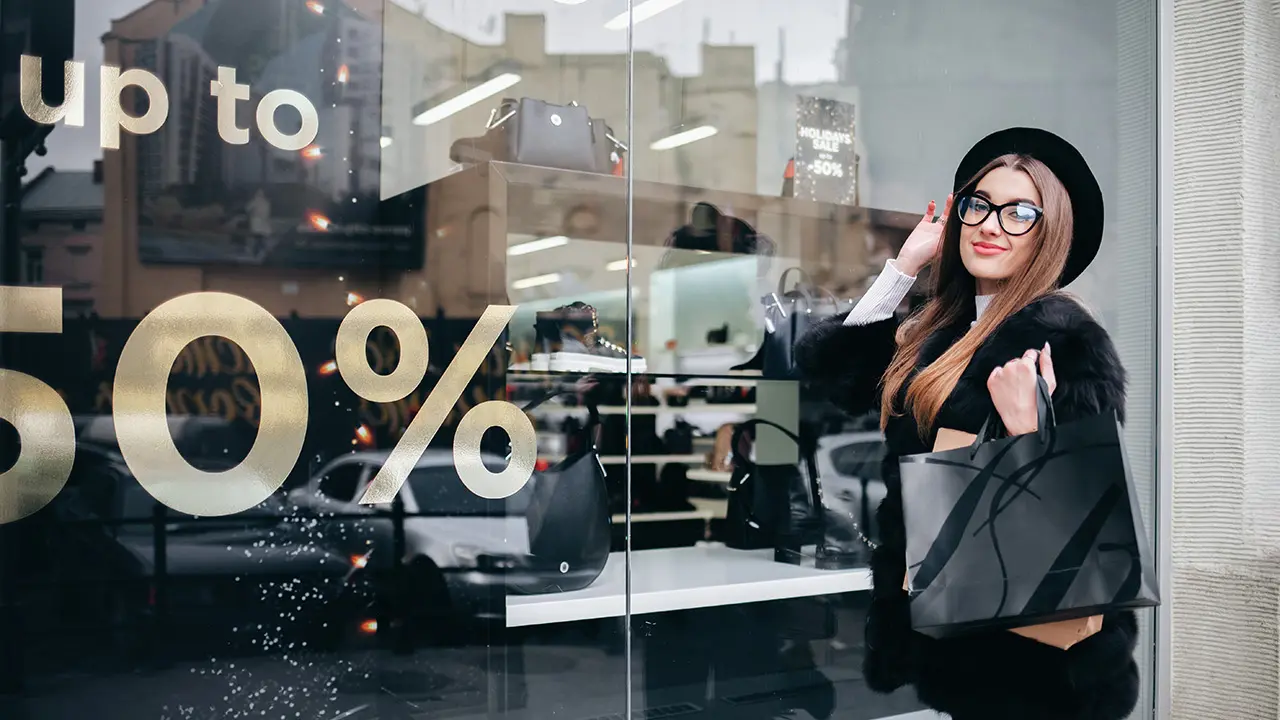 Fachada de tienda moderna con vinilos para escaparates instalados profesionalmente comunicando rebajas y nueva colección.