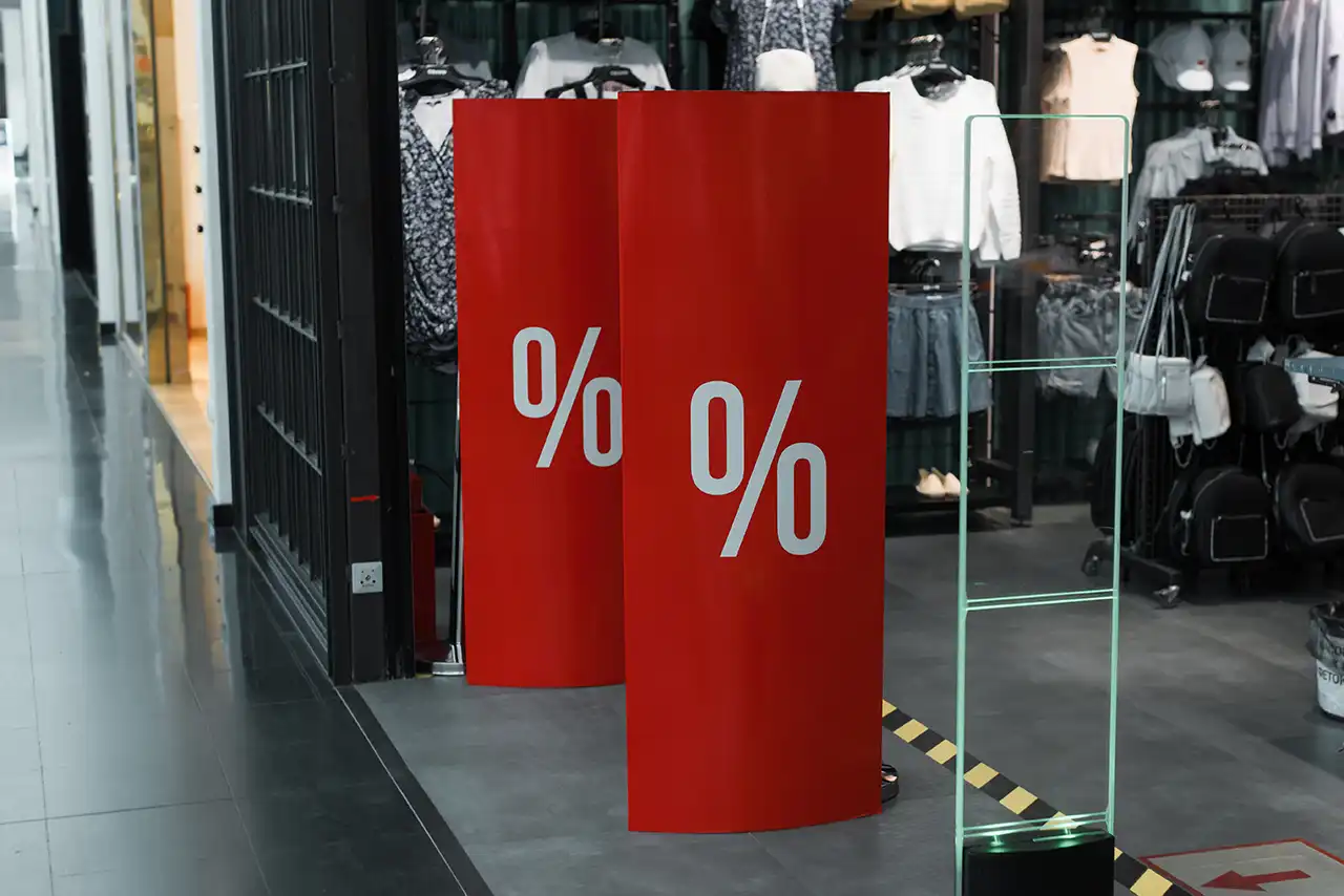 Entrada de una tienda retail moderna con arcos antihurto cubiertos por tótems publicitarios de cartón personalizados con una promoción.