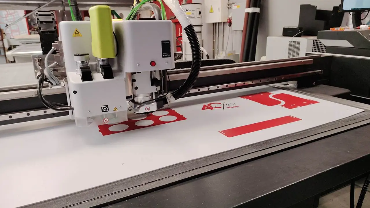 Mesa de corte digital automatizada realizando el troquelado de un expositor de cartón para una campaña PLV express.