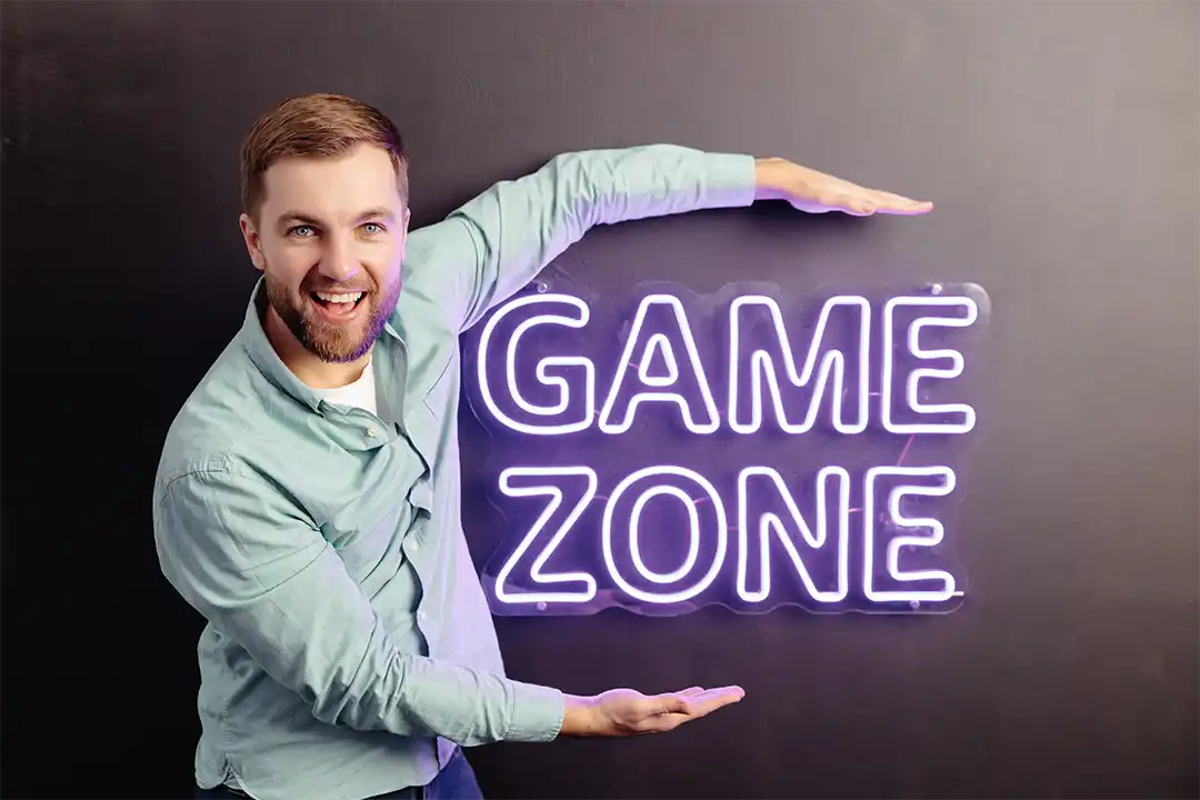 Zona de experiencia gaming en tienda de tecnología con paneles oscuros y rótulos corpóreos retroiluminados.